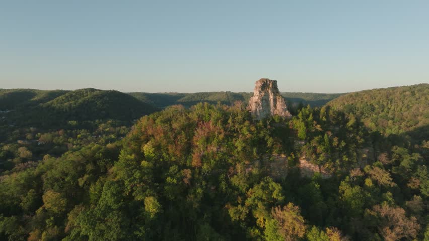 Scenic aerial view of Sugarloaf Bluff in Winona, Minnesota, surrounded by autumnal forests and a serene valley at sunrise.