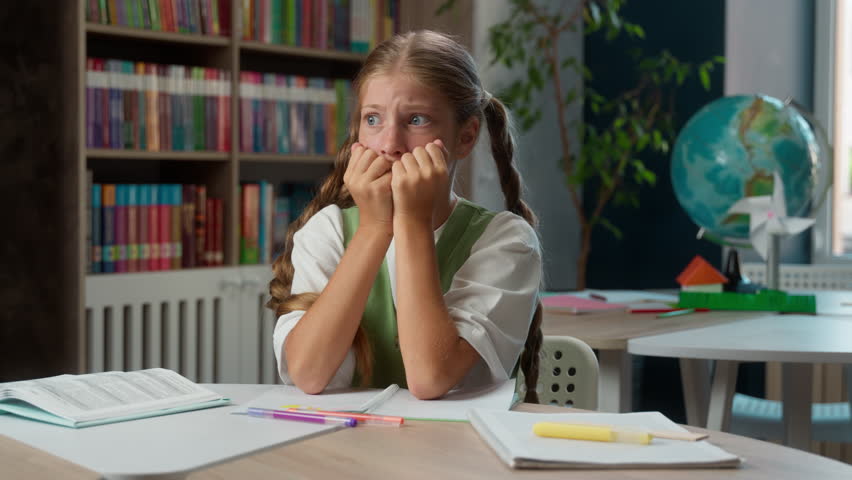 Scared worried anxious Caucasian little girl fearful frightened school child kid nervous pupil schoolgirl student primary education learner biting nails afraid fail test exam worry problems classroom - Powered by Shutterstock - Get 15% off with code: PIKWIZARD15