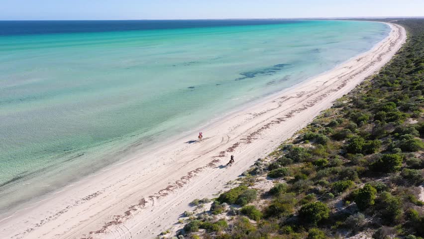 Horse riders gallop across Flaherty Beach on Yorke Peninsula, South Australia - aerial view