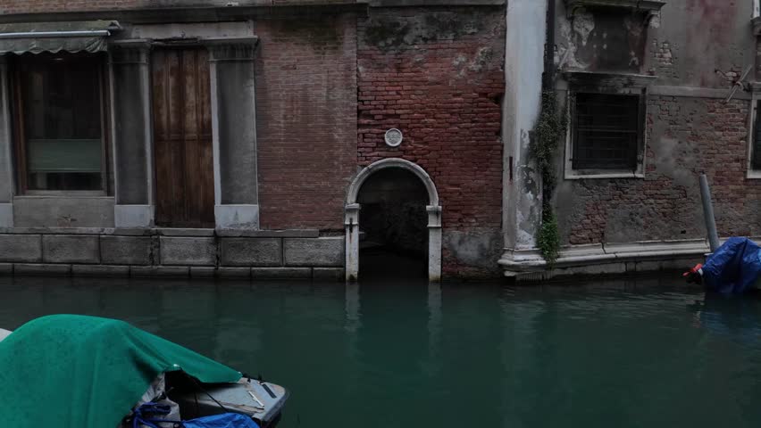 Classic venetian architecture and channel cityscape. Quiet narrow channel with turquoise water and old buildings with boat and bridge. No people