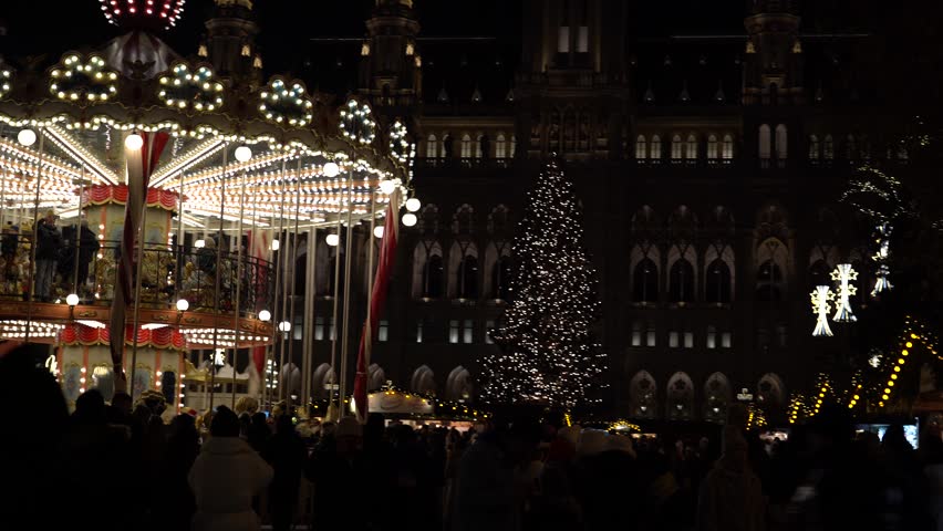 Vienna, Austria - December 13, 2024: Evening view of Rathaus Park and Vienna City Hall. Christmas market. New Year's illumination. People on the square.