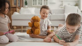 Cute mixed race children spending time together at home, little friends playing. Black and Caucasian kids drawing on floor, happy funny toddler playing with teddy bear, diversity of people ethnicity - Powered by Shutterstock - Get 15% off with code: PIKWIZARD15