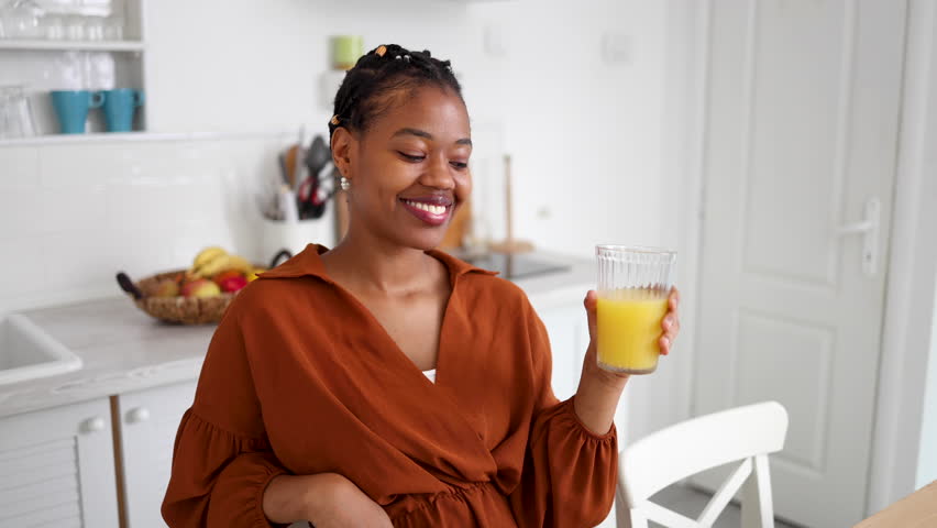 Young African American woman enjoying at her home and refreshing with juice