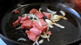 Sausages and onions sizzle in a hot cast iron skillet over an outdoor fire. The smoky aroma fills the air as these ingredients cook to perfection, inviting passersby to enjoy the meal. - Powered by Shutterstock - Get 15% off with code: PIKWIZARD15