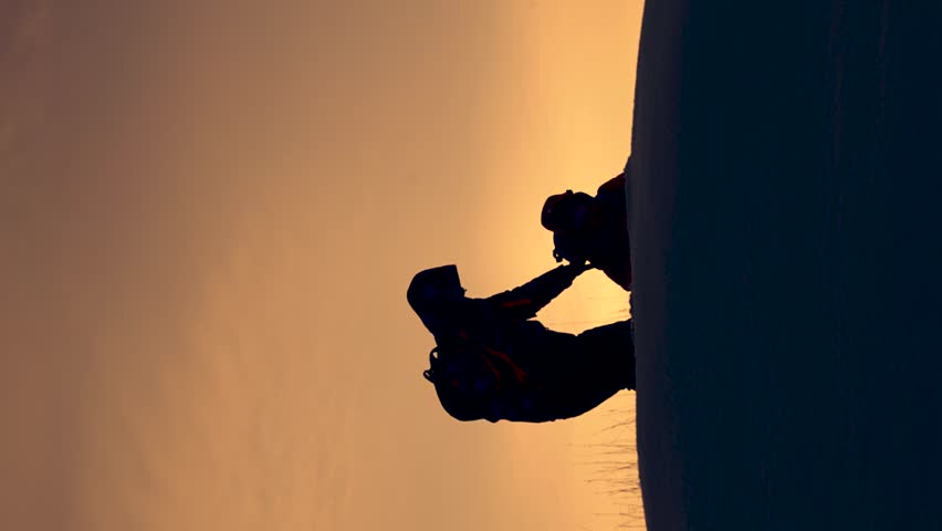 Business people met on top of success. Hiker, man, woman, Alaskan travelers go to top of snowy hill, rejoice in victory against winter sunset. Team work of people. Business teamwork, victory success