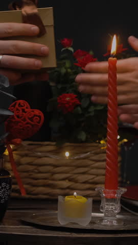 Vertical video. St. Valentines day concept. Man in love giving gift to his beloved during candlelit dinner. Romantic date of loving couple.