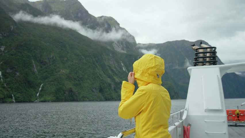 Asian woman enjoying the view of Milford Sound during ferry cruise on vacation at Fjordland national park, New Zealand