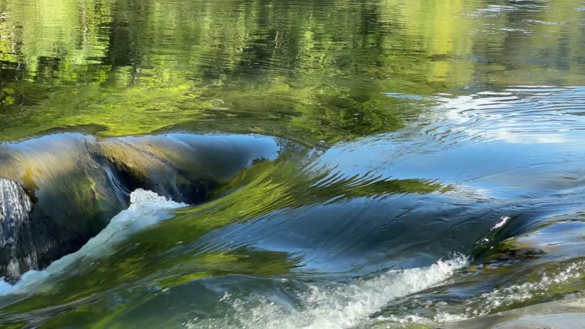 Water flow between the rocks in the waterfall on a mountain river in the Carpathian mountains, view close-up when panning in sunny autumn day 
