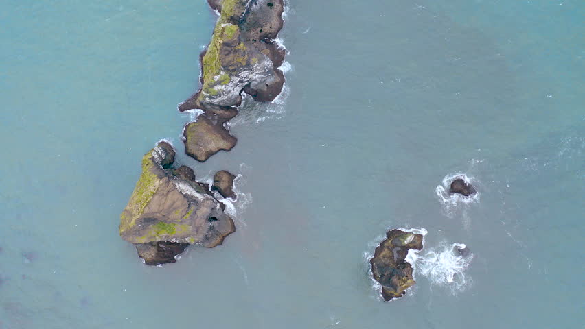 Aerial view of Reynisdrangar basalt sea stacks situated in the ocean, under the mount Reynusfjall and close to the villaje of Vik in the south of Iceland.