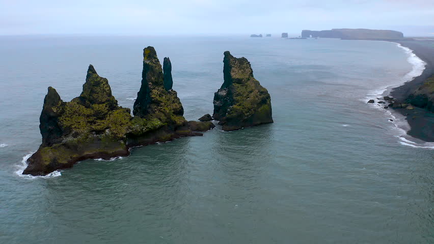 Aerial view of Reynisdrangar basalt sea stacks situated in the ocean, under the mount Reynusfjall and close to the villaje of Vik in the south of Iceland.