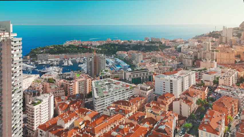 Aerial view of the city center of the Principality of Monaco. The scene showcases luxury yachts moored in Monaco Bay, the Palais Princier de Monaco, and luxury apartment buildings of Monte Carlo 