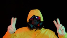 Cyberpunk dancer in hazmat suit performing in neon lights. Futuristic character in protective mask making peace sign on dark background - Powered by Shutterstock - Get 15% off with code: PIKWIZARD15