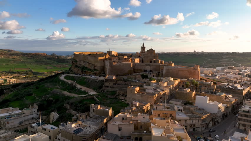 4k Aerial view of Historic fort, Citadel Ruins on cliff overlooking valley at sunset with lush greenery in the background. island Gozo. Malta