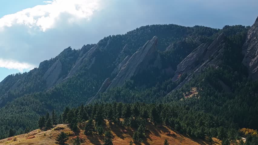 Aerial telephoto of Boulder Colorado iconic Flatirons with stunning evergreen trees, tracking left