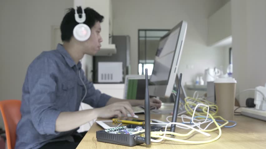 Ethical hacker is working on research The laptop has stickers on it. The man is typing on the laptop and he is focused on his work