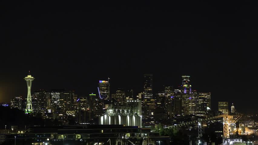 Timelapse of a full moon ascending over the vibrant Seattle skyline, highlighting the city