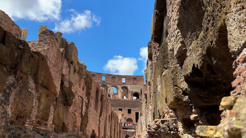 Interior underground corridors of the Colosseum, tilt up sideways pan of the catacombs in blue sky
