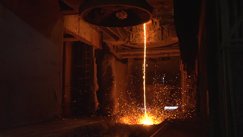 Industry Cast Process in Blast Furnace. Jet of red-hot metal pours at factory. Beautiful red-hot metallic liquid is poured into molds to solidify. Metallurgical plant with incandescent metal streams.
