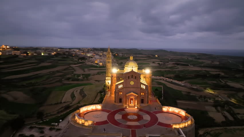 Aerial view of Stunning view of a illuminated Basilica of Our Lady of Ta' Pinu on a hilltop with dramatic sky and landscape. Gozo. Malta