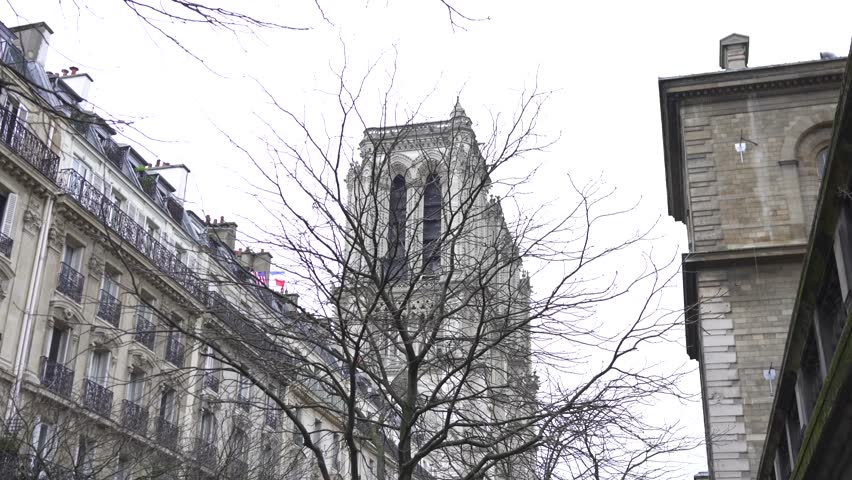 The iconic tower of Notre Dame Cathedral rises elegantly amid the historic architecture and charming surroundings of Paris, France.