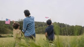 back view of mother and sons  with usa flag on field. 4th july independence day. - Powered by Shutterstock - Get 15% off with code: PIKWIZARD15