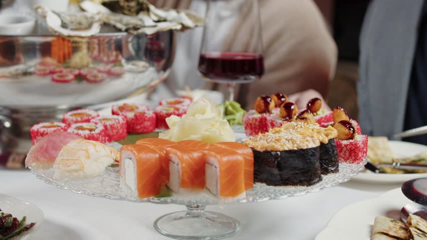 Guests Sharing Sushi Rolls with Chopsticks at a Party Table