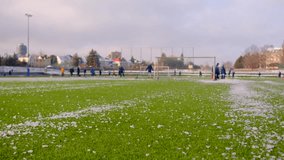 Sports ground covered in ice chunks, start of training. snowy grass field is the venue for a soccer training session with players in the background - Powered by Shutterstock - Get 15% off with code: PIKWIZARD15