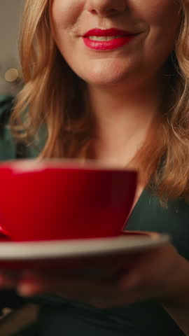 Close-up portrait of attractive pretty cute dreamy cheery girl drinking aromatic cacao latte from a red cup. Happy woman relaxing and smile in house indoors with christmas x-mas atmosphere decoration