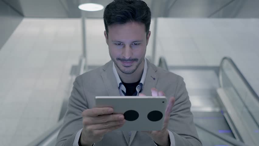 Man is Shown Using a Tablet Screen in the Midst of a Busy Street