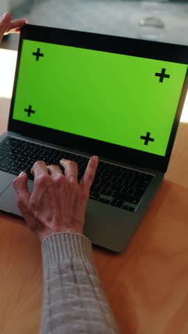 Vertical video, Senior woman working from home on a laptop with green screen. Perfect for mockups or tutorials. Add your own content.