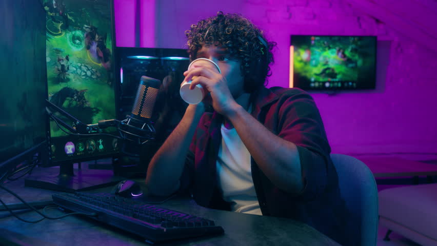 Bored Indian Arabian Latino man tired guy monitor computer networking cyberspace programmer gamer streamer play drink coffe male pc workplace late technology internet cellular online insomnia networks