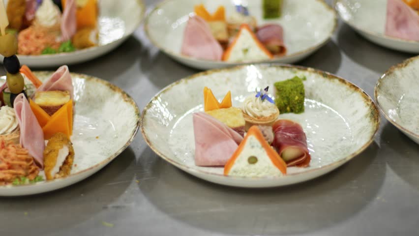 Kitchen staff arranges plates of appetizers for a catered event