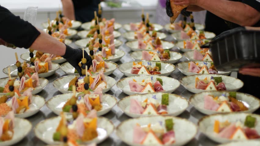 Kitchen staff arranges plates of appetizers for a catered event