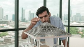 Professional architect engineer using pencil measuring model roof length at modern office with skyscraper, cityscape view. Skilled project manager or businessman check house construction. Tracery - Powered by Shutterstock - Get 15% off with code: PIKWIZARD15