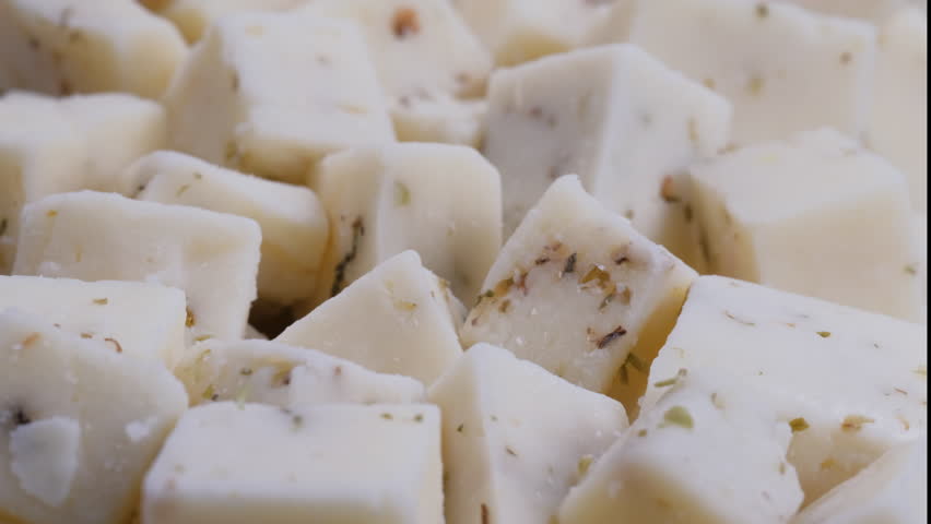 Close-up view of flavorful herbed cheese blocks in close detail. Slider shot. Depth of field, selective focus. Cooking , culinary, vegetarian food concepts. 4K 