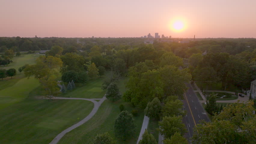 Stunning sunset over Forest Park and Lindell Blvd in St. Louis, Missouri. Vibrant evening sky, cityscape, lush trees, serene views, iconic park, warm hues, peaceful ambiance, and urban charm captured