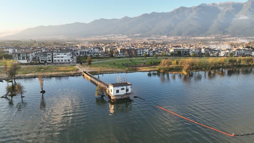 4K aerial view of Erhai Lake in Dali, Yunnan, China.  Buildings line the lakeshore, mountains in the background.