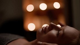 Masseur gently gives a relaxing facial massage to a serene woman in a candlelit massage room, creating a soothing and tranquil environment - Powered by Shutterstock - Get 15% off with code: PIKWIZARD15