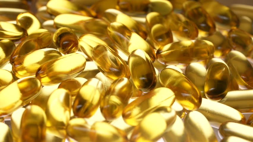 Fish oil capsules with omega 3 and vitamin D on white background, close up, rotates. Golden fish oil in gelatin capsules