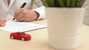 Man buying or selling car. Businessman signing auto insurance document or lease paper. Person writing signature on contract or agreement. Red toy car on the table, selective focus - Powered by Shutterstock - Get 15% off with code: PIKWIZARD15