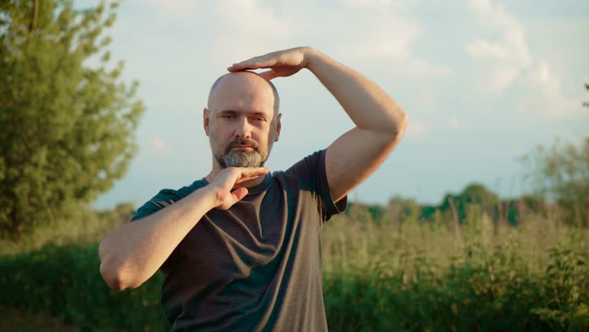 Bald male performing creative head dance with closed eyes and peaceful expression. Guy with bald head moving head rhythmically while expressing calm emotions. Male showing unique head movement dance