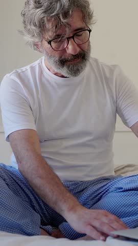 Senior man transitions from stress to tranquility, using headphones for a meditative experience. Vertical video