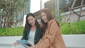 Asian Businesswomen Collaborating Outdoors: Sharing Ideas and Plans with a Tablet in an Urban Greenery Setting. Professional Asian Women Discussing Digital Marketing. Remote work online outdoors - Powered by Shutterstock - Get 15% off with code: PIKWIZARD15
