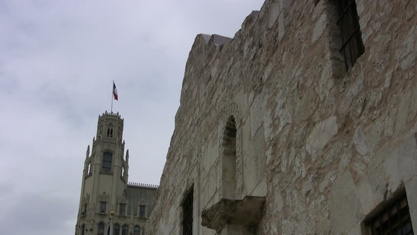 Video closeup front of the Alamo shrine San Antonio Texas. Texas flag. Emily Morgan Hotel background.  Historic famous building Texas independence battle with Mexico. 