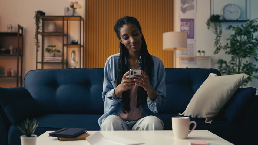 Happy African American woman reads a message on her phone, pleasant conversation - Powered by Shutterstock - Get 15% off with code: PIKWIZARD15