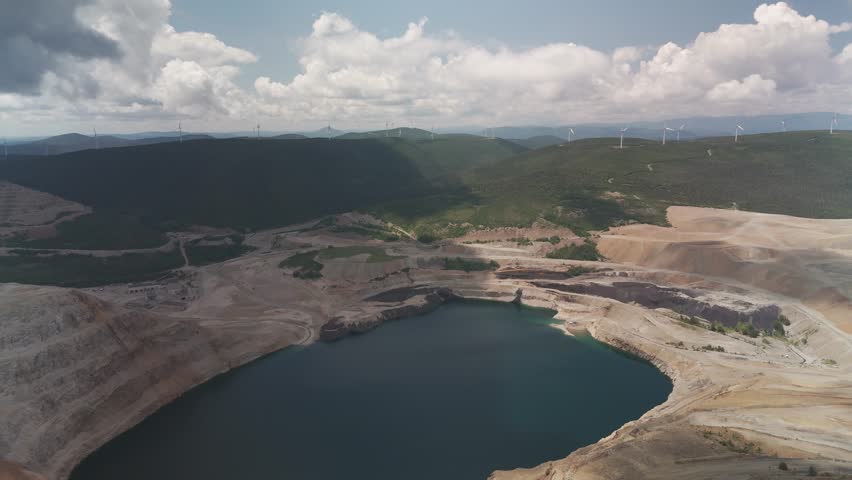 An aerial done shot of stunning view of a lake in the middle of the copper mine of Murdochville in Gaspésie during daytime. Backward movement.