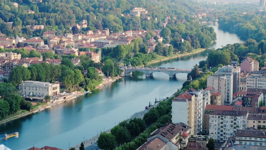 An aerial drone view highlighting the Mole Antonelliana, flanked by the Po River and a mix of Turin’s historic and modern architecture.