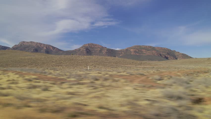 A shot of Flinders Ranges mountains in Australia from a moving car, the foreground is mowing fast in front of the camera