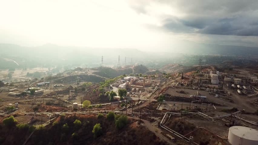 Aerial wide shot of industrial factory with pipelines and sunlight in California. Oil factory with oil wells in suburb,