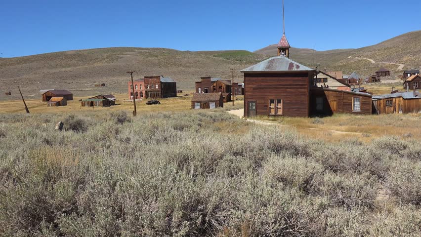 BODIE - 10.21.2024 - A run-down church stands in front of residential run-down buildings in the ghost town of Bodie, California.
